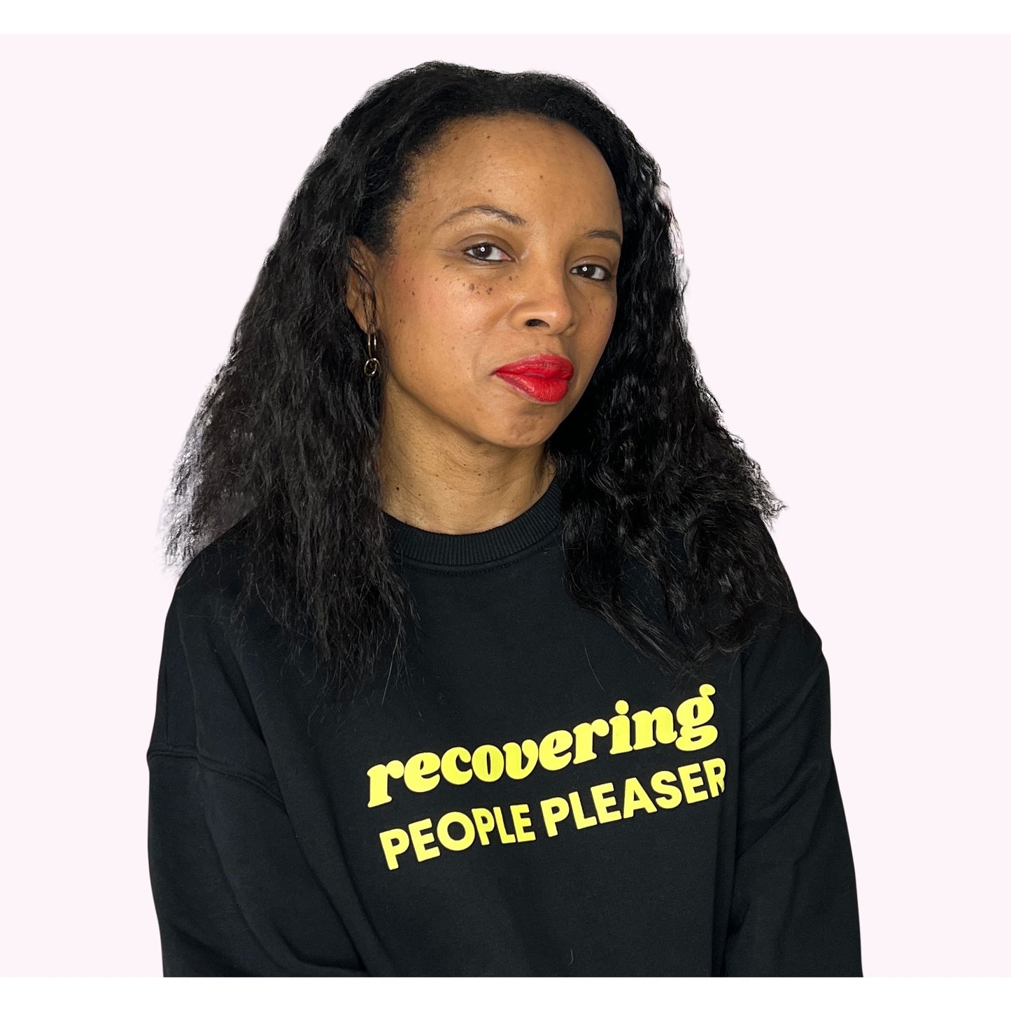 Natalie Lue wearing the recovering people pleaser sweatshirt in black with neon yellow ink